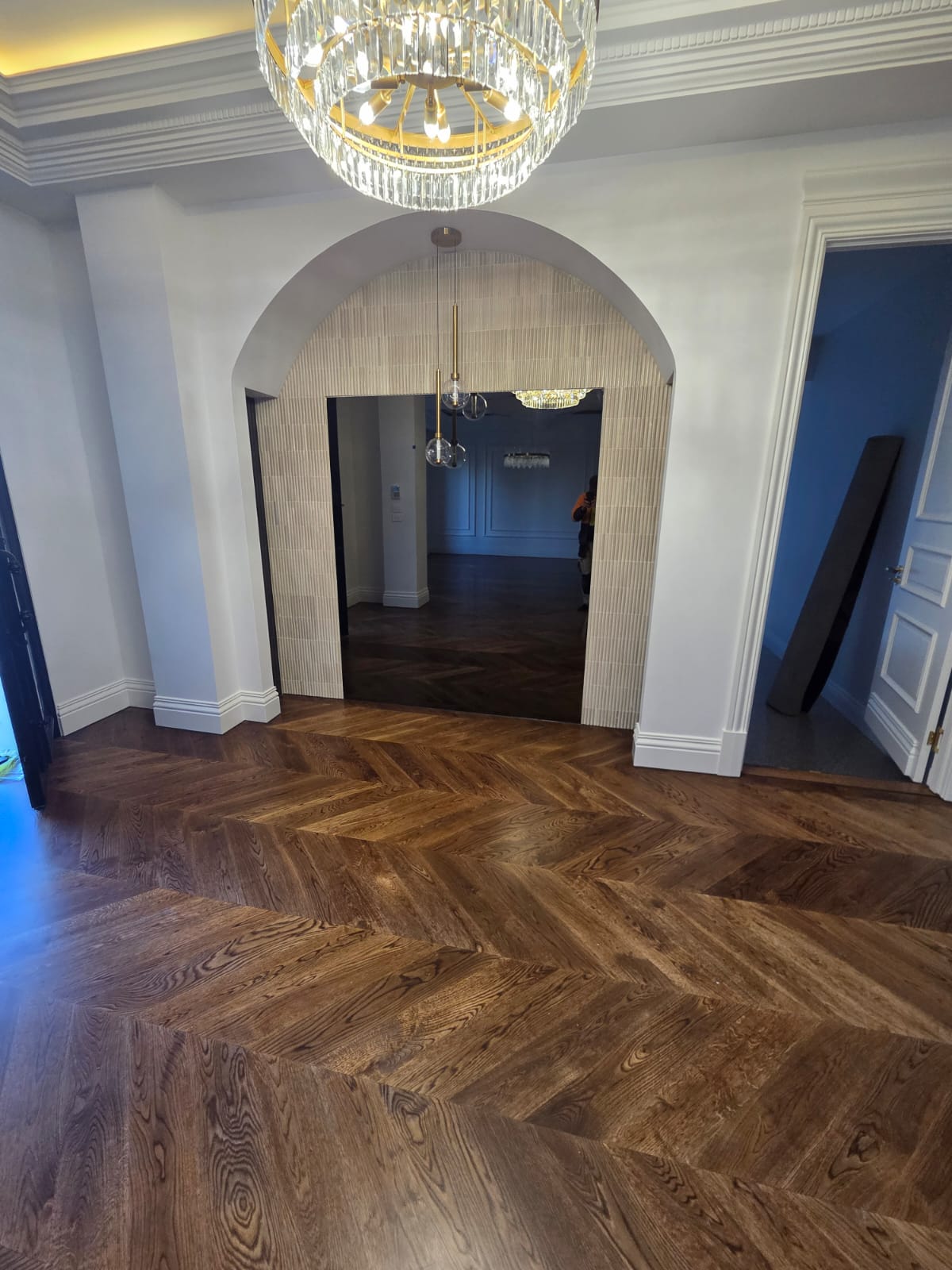 Arched entryway with fluted tile detailing and herringbone timber flooring