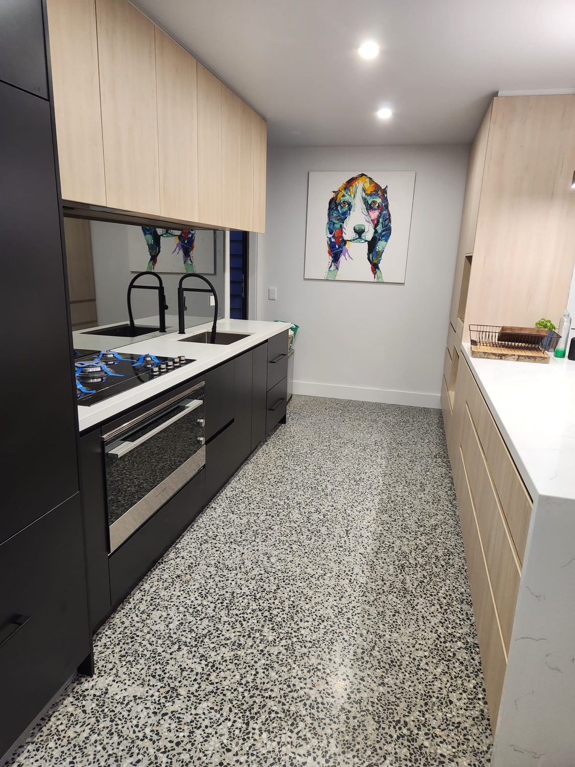 Black and oak galley kitchen with mirrored splashback