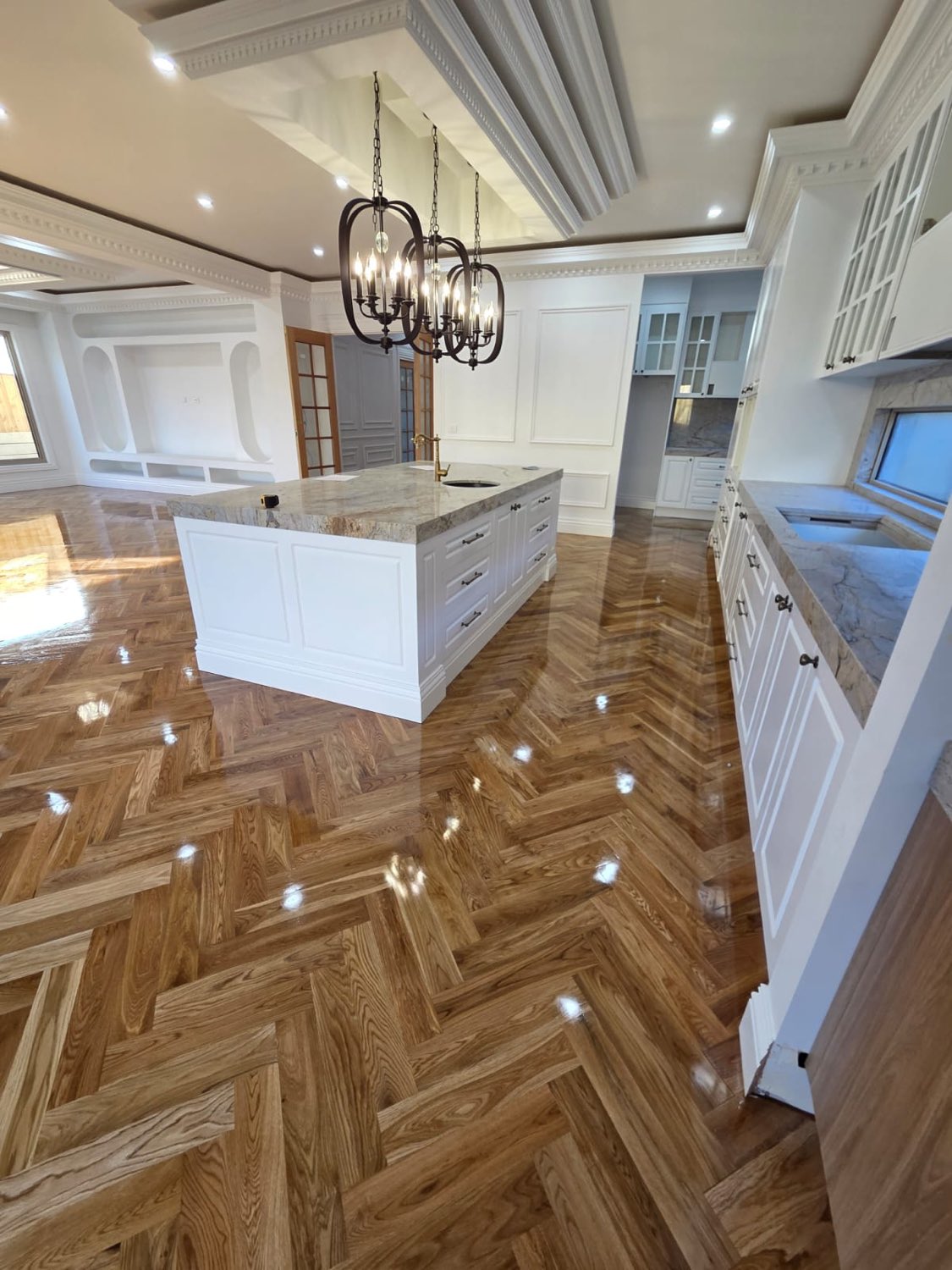 Classic white kitchen with herringbone timber flooring and pendant chandelier