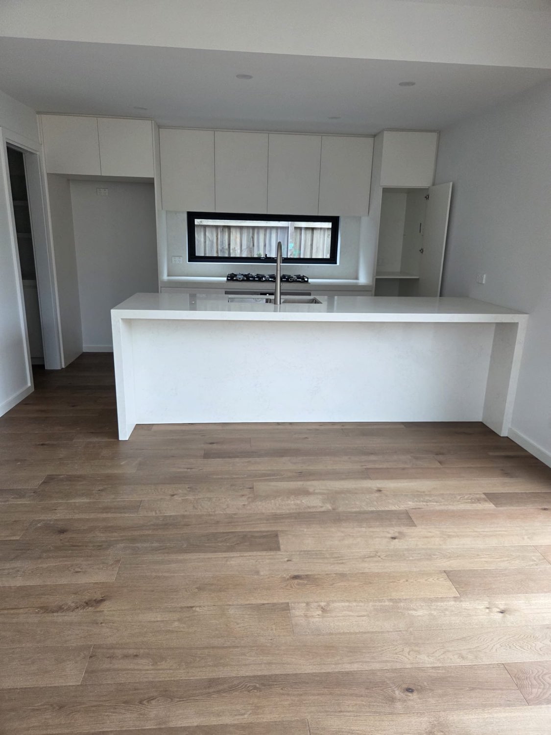 Minimal white kitchen with stone island bench