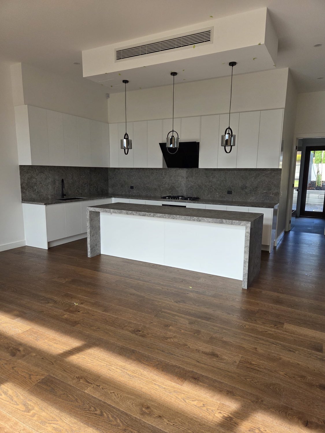 White kitchen with stone splashback and pendant lighting