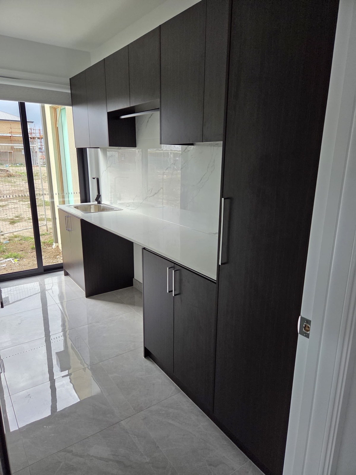 Dark laundry cabinetry with stone benchtop