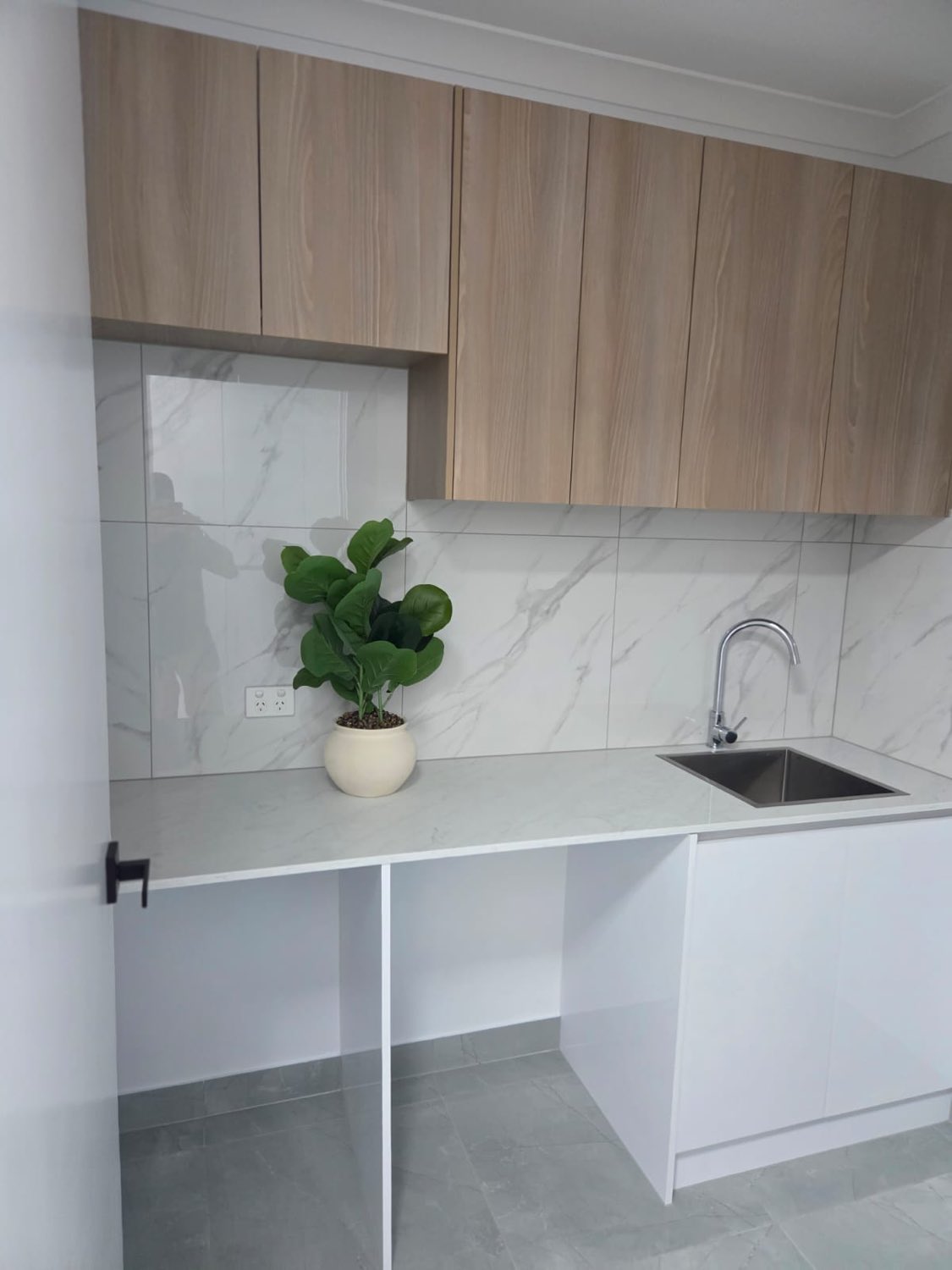 Oak laundry cabinetry with marble splashback