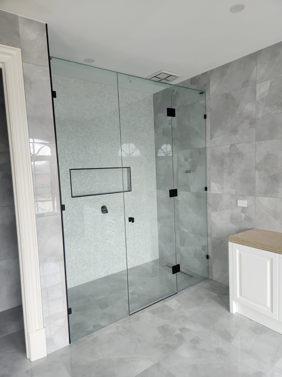 Frameless shower screen installation with tiled niche for a modern Melbourne bathroom