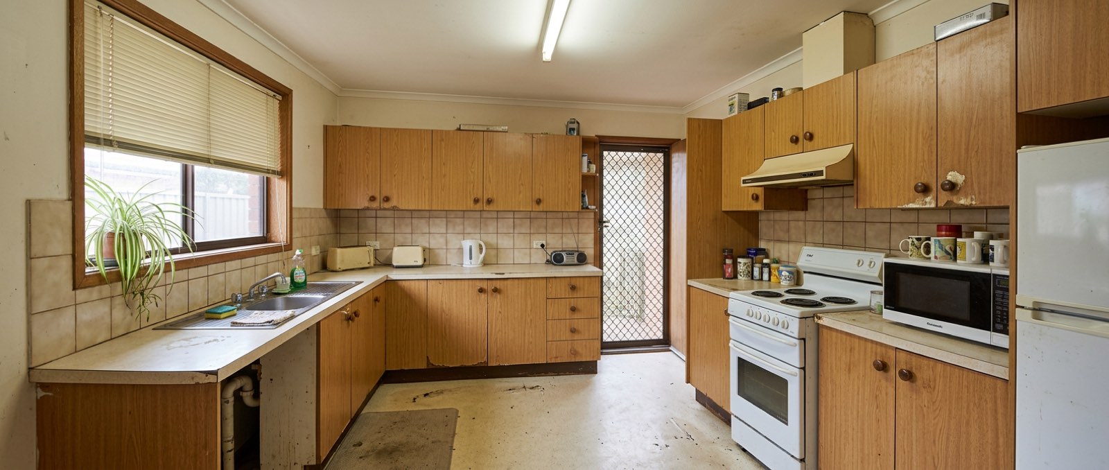 Dated kitchen with worn oak laminate cabinetry before renovation