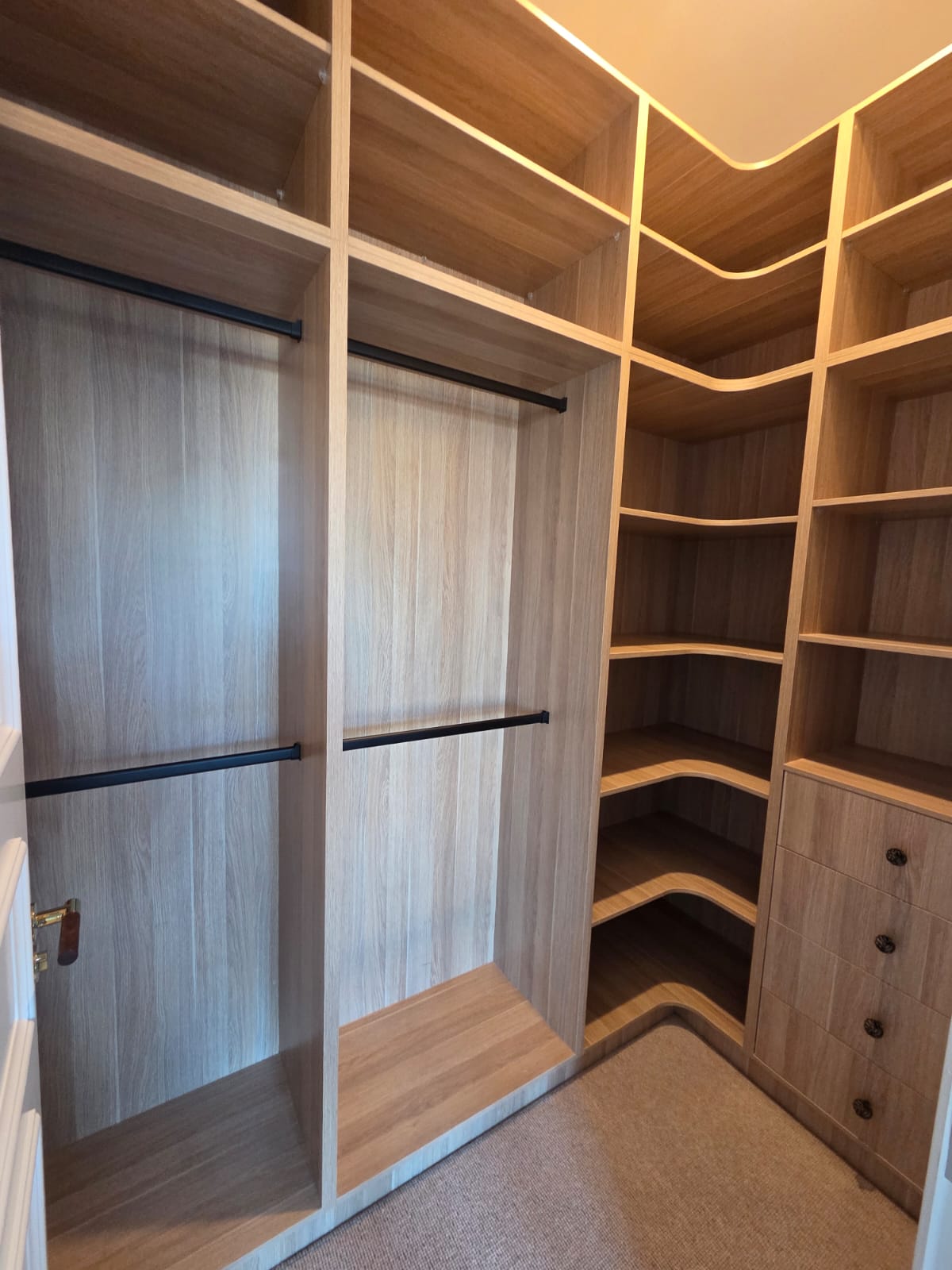 Oak walk-in wardrobe with full-height corner shelving and black hanging rails